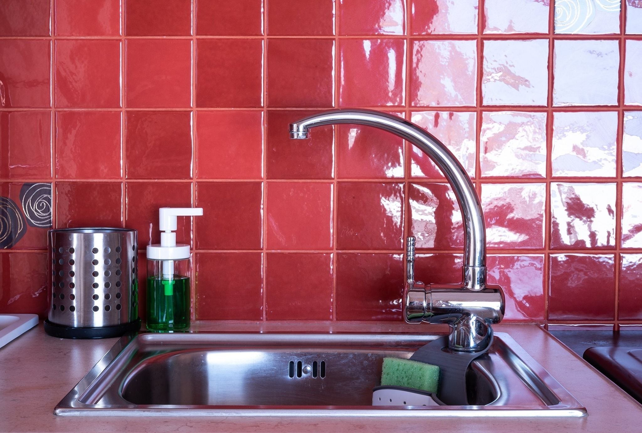 A kitchen sink with a chrome faucet, a soap dispenser, and a grater on the countertop.