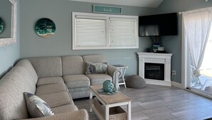 A living room with a sectional sofa, a fireplace, and a television mounted on the wall.