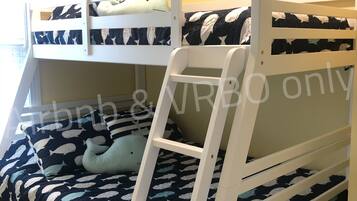 Un letto a castello con una scala, un cuscino e una coperta con motivo di delfini.