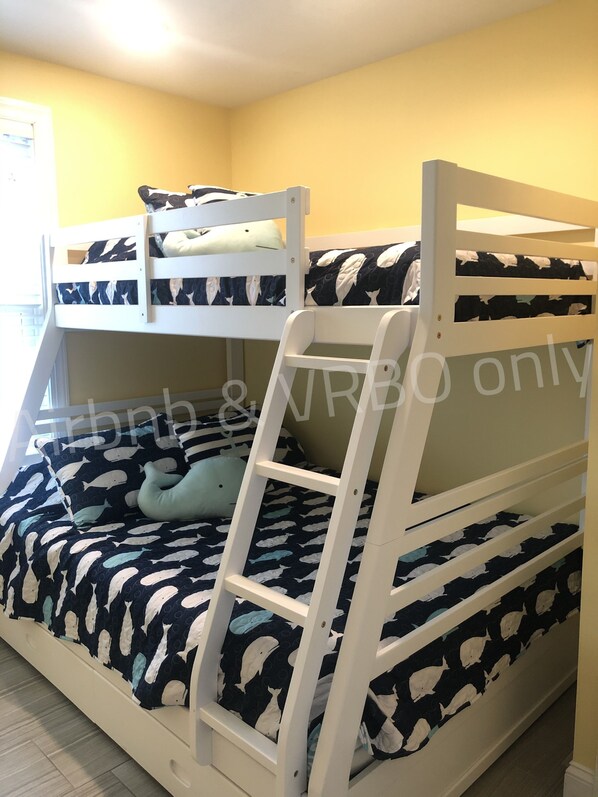 Una cama litera con escalera, un almohadón y una manta con estampado de delfines.