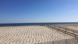A sandy beach with a wooden fence and a clear blue sky.