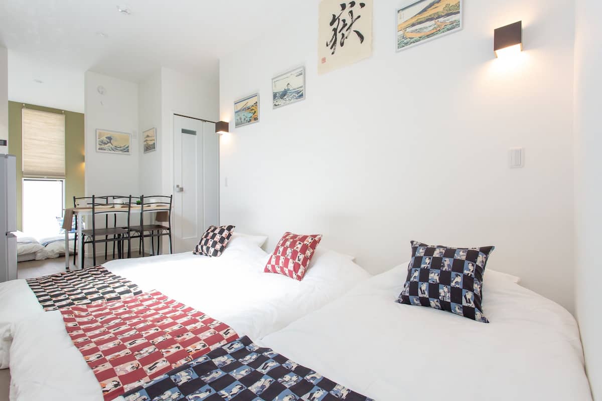 A hotel room with a large bed, two pillows, a quilt, a desk, and chairs.