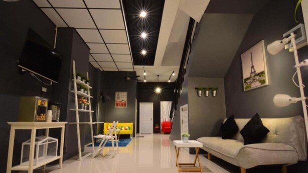 Una sala de estar moderna con un sofá, un televisor montado en la pared e iluminación empotrada en el techo.