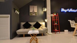 Un vestíbulo de hotel moderno con un sofá, una mesita, un estante rojo y un letrero de neón.