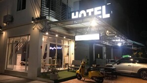 Un hotel con un cartel llamativo que dice 'HOTEL', un área de estar al aire libre cubierta y una moto estacionada.