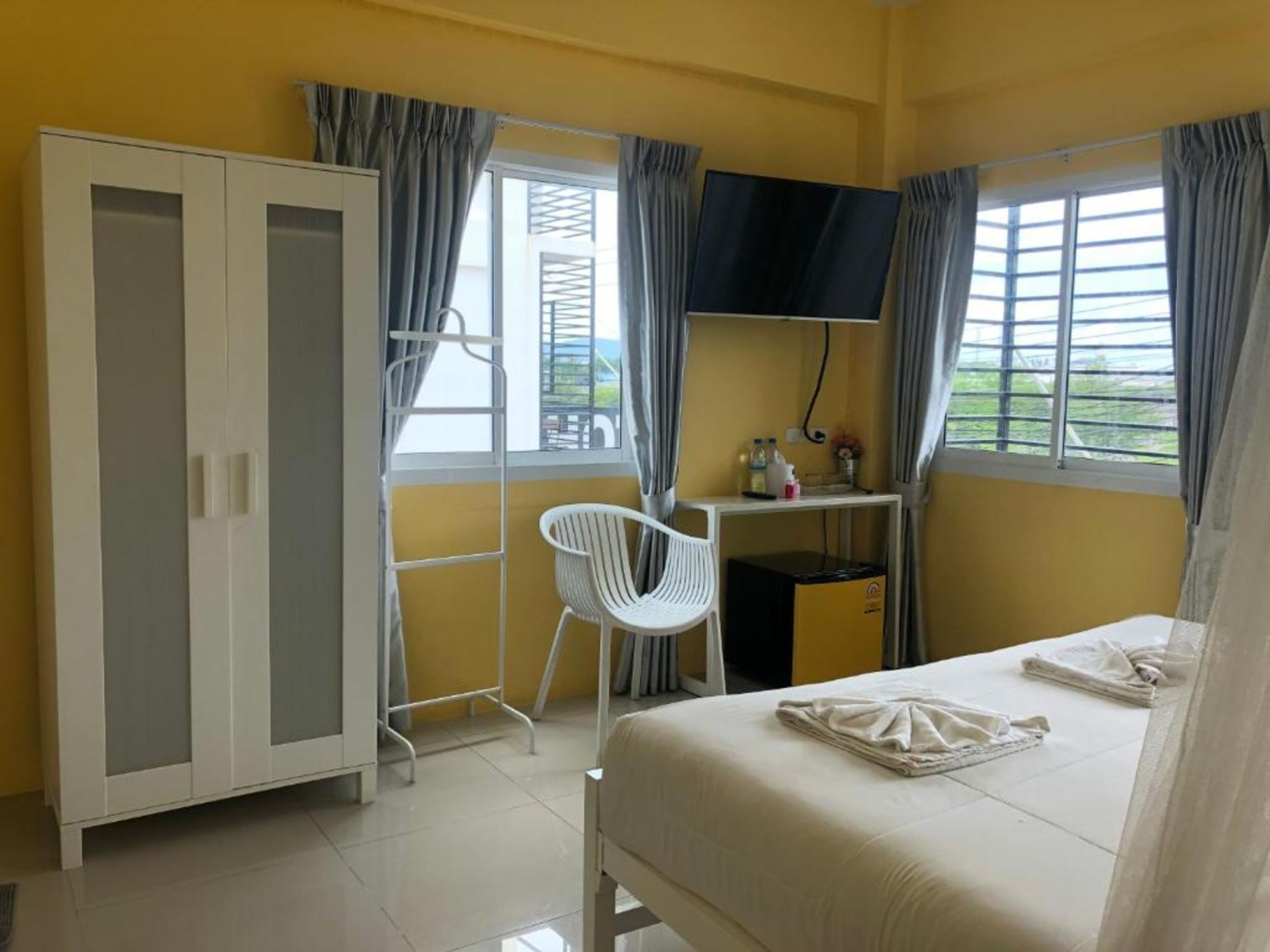 A bedroom with a bed, a wardrobe, a desk with a TV, and a chair.