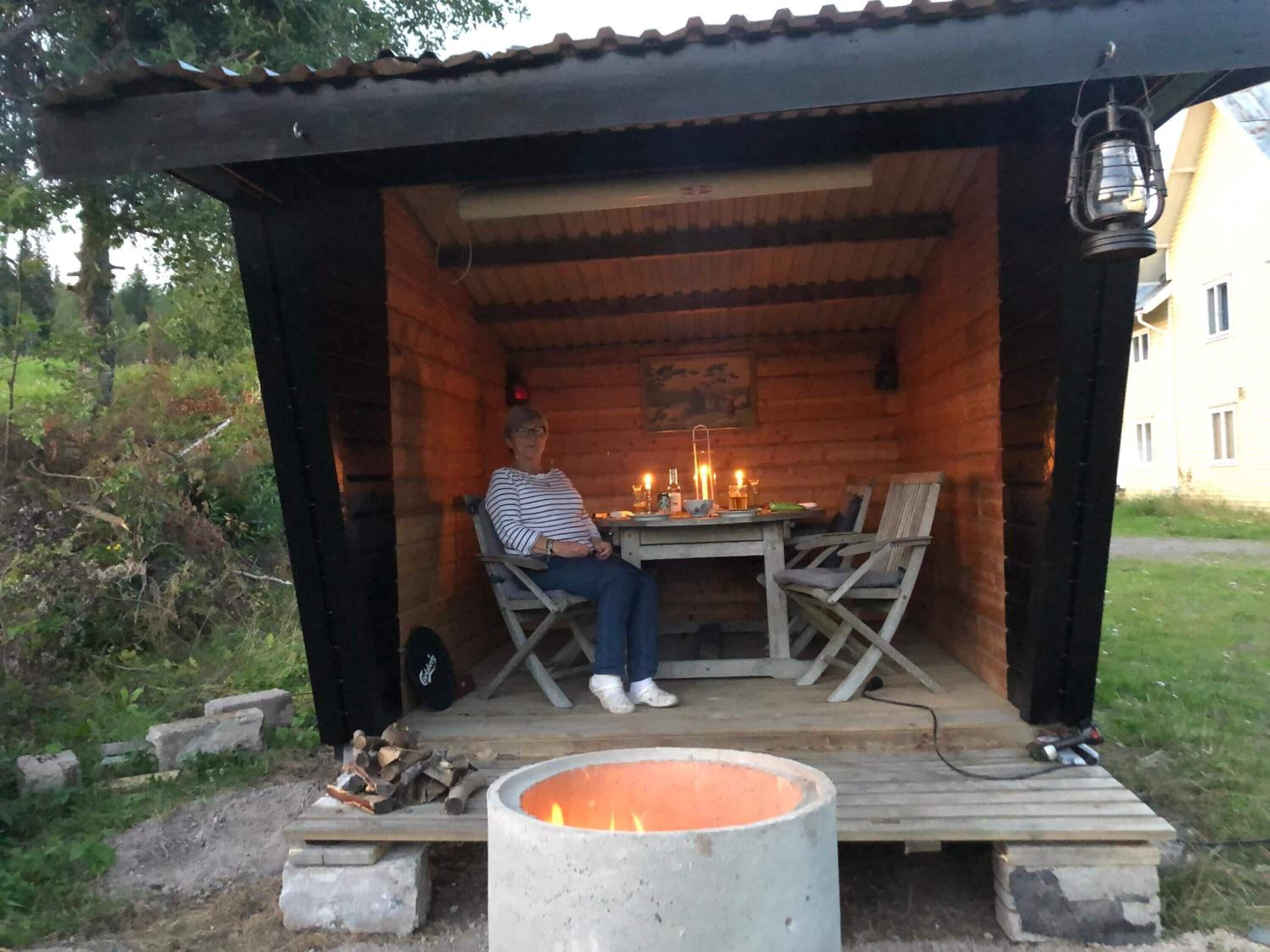 Una cabaña rústica de madera con un brasero y una mesa con velas.