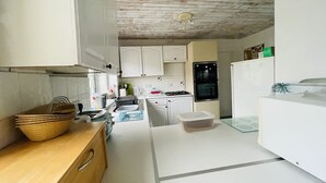 Una cocina compacta con armarios blancos, encimera de madera, un fregadero, una estufa y un refrigerador.
