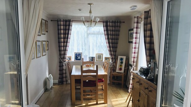 Un comedor con una mesa y sillas de madera, una ventana con cortinas y vistas al exterior.