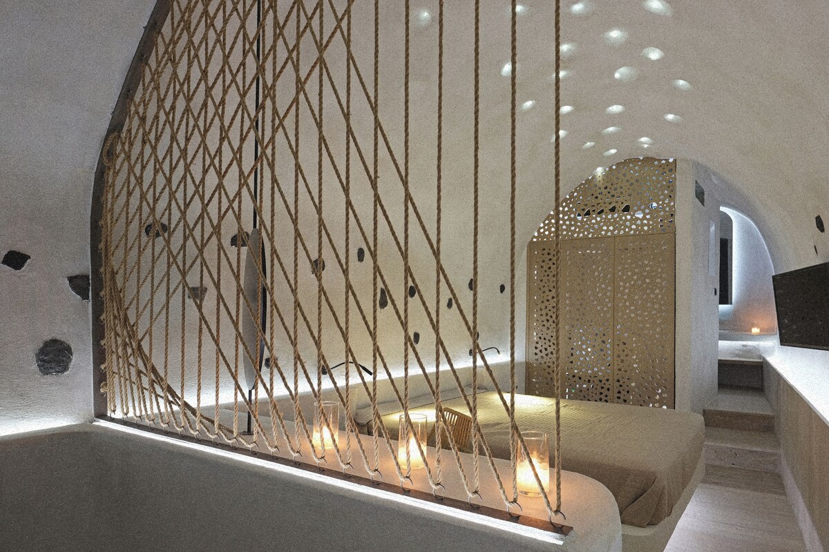 Un interior moderno con una barrera de cuerda, una zona de estar con velas y una escalera.