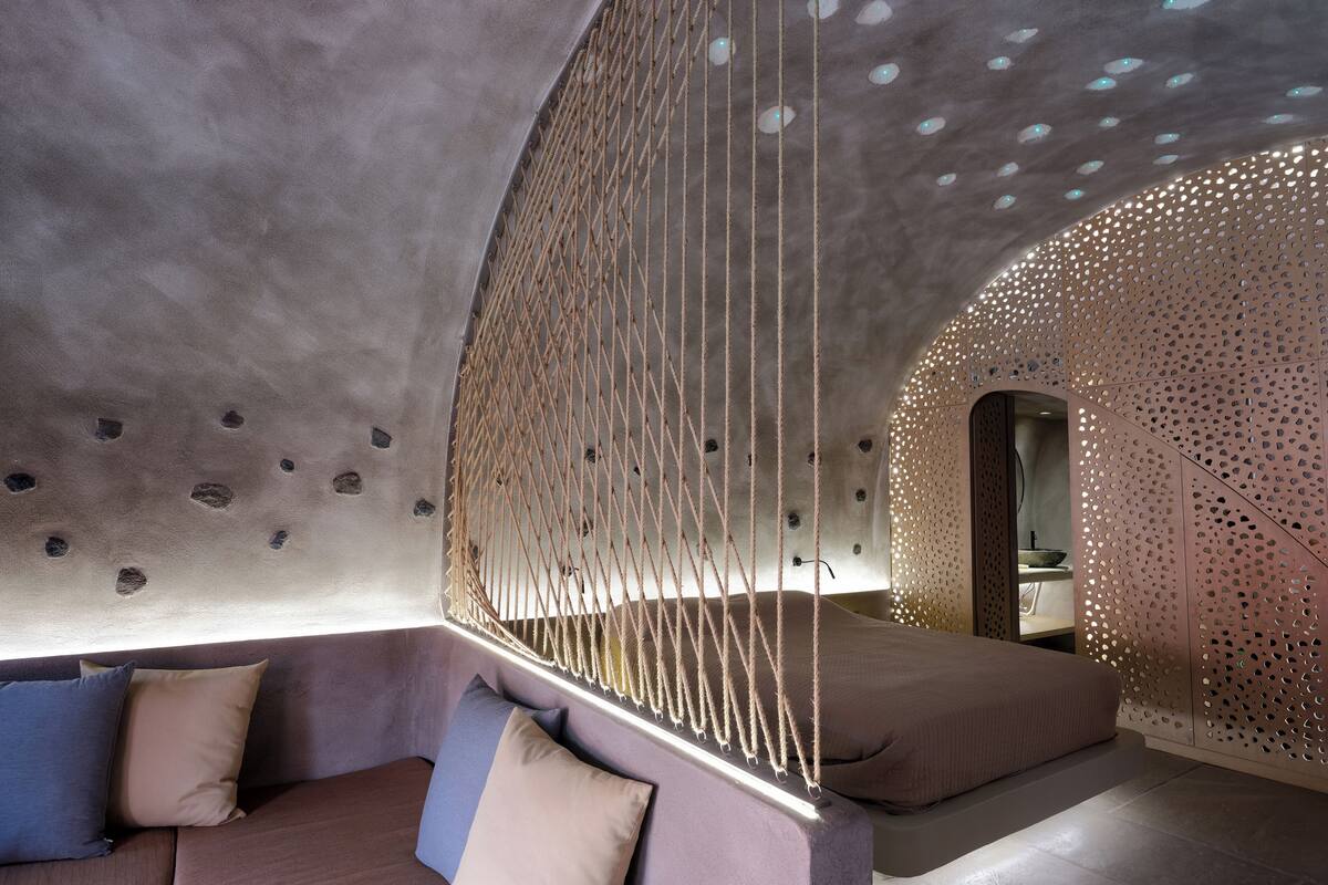 A room with a curved ceiling, a hanging rope structure, and a seating area with cushions.
