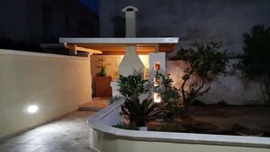A courtyard with a central fountain, surrounded by a low wall and a few potted plants. - Magnolia House (Montalbano)