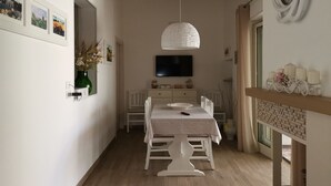 A dining area with a white table, chairs, and a hanging light fixture. - Magnolia House (Montalbano)