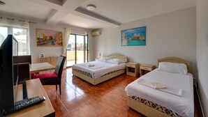 Ein Hotelzimmer mit einem Bett, einem Schreibtisch mit Fernseher und Fernbedienung, einem Sessel und einem Bild an der Wand.