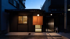 Ein traditionelles japanisches Gebäude mit dunkler Fassade, einem Ziegeldach und einem kleinen Eingang mit einer Schiebetür.