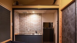 Ein kompakter Wohnraum mit einer Couch, einer Küchenzeile mit Ziegelrückwand und einem dunklen Schrank.