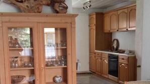 A kitchen with wooden cabinets, a dining table, and a built-in oven. - off in the summer 08 (Jabel)