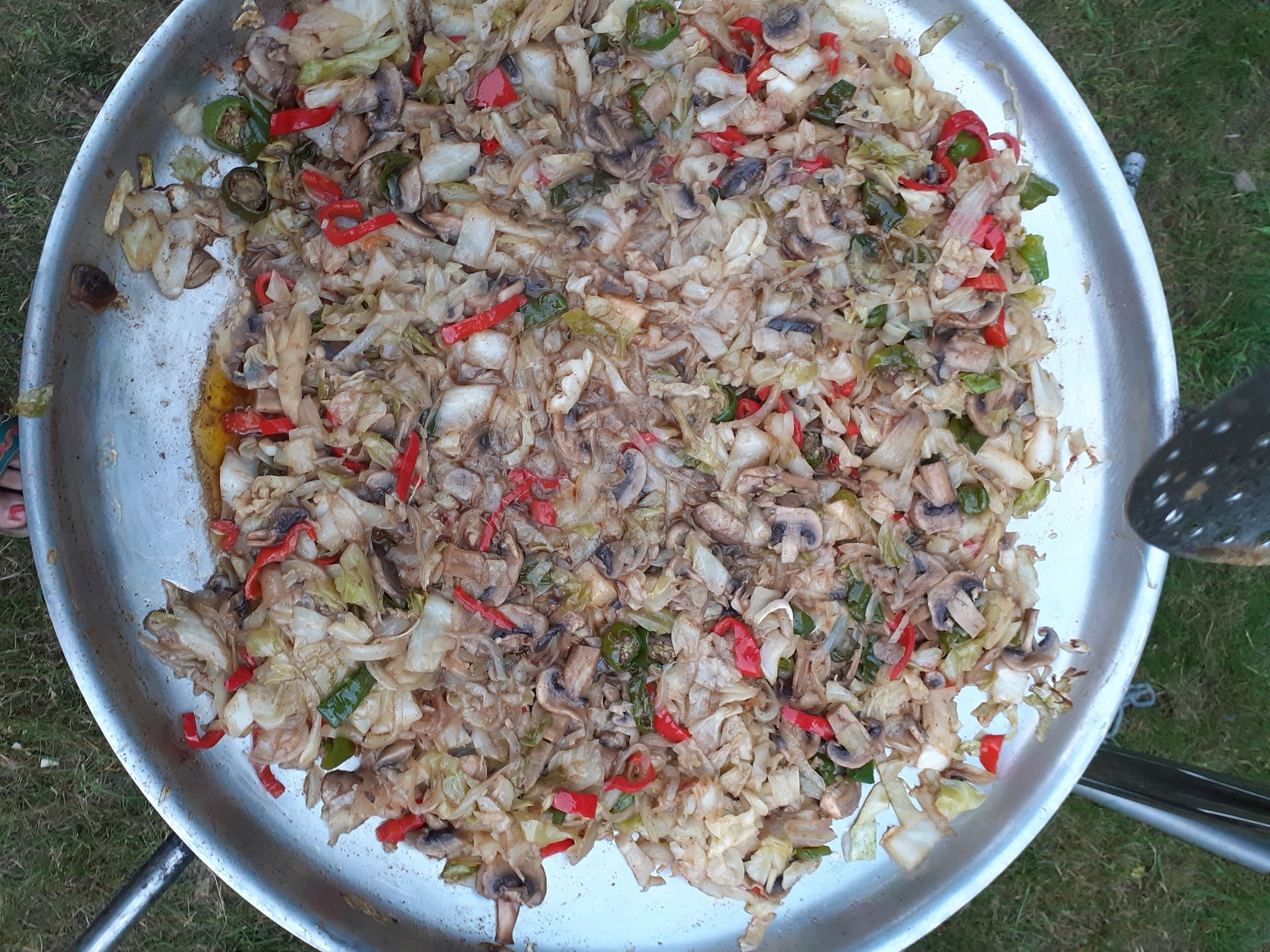 Eine große Metallpfanne mit einem gebratenen Gericht aus Gemüse und Fleisch.