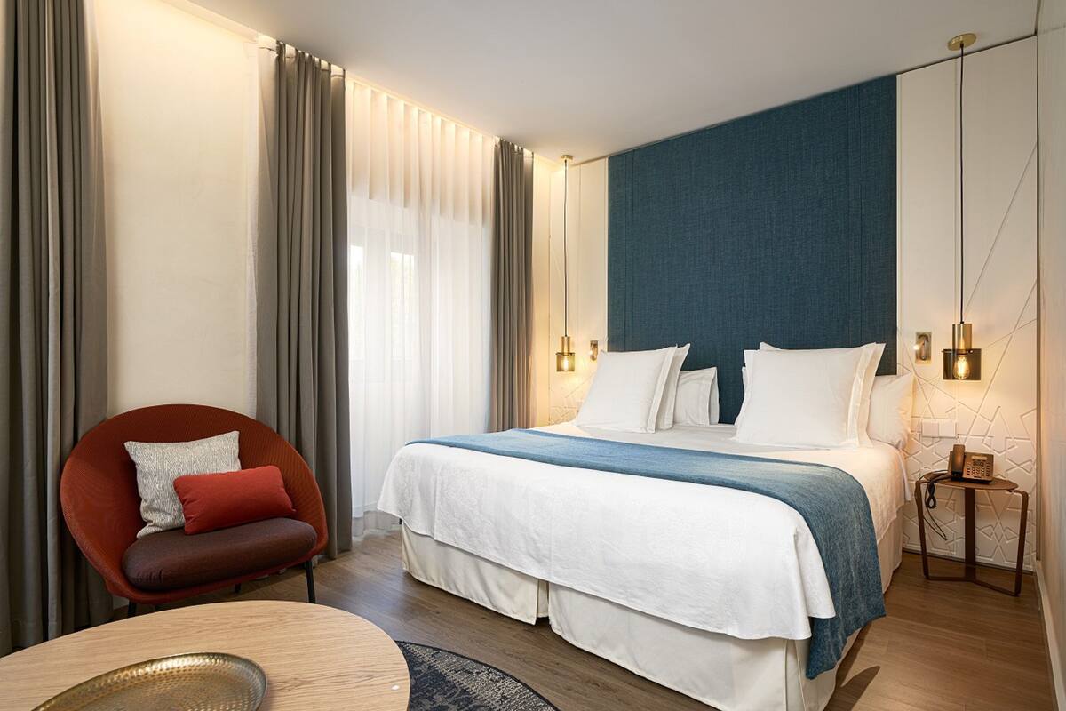 Ein modernes Hotelzimmer mit einem großen Bett, einem roten Sessel und einem kleinen Tisch.