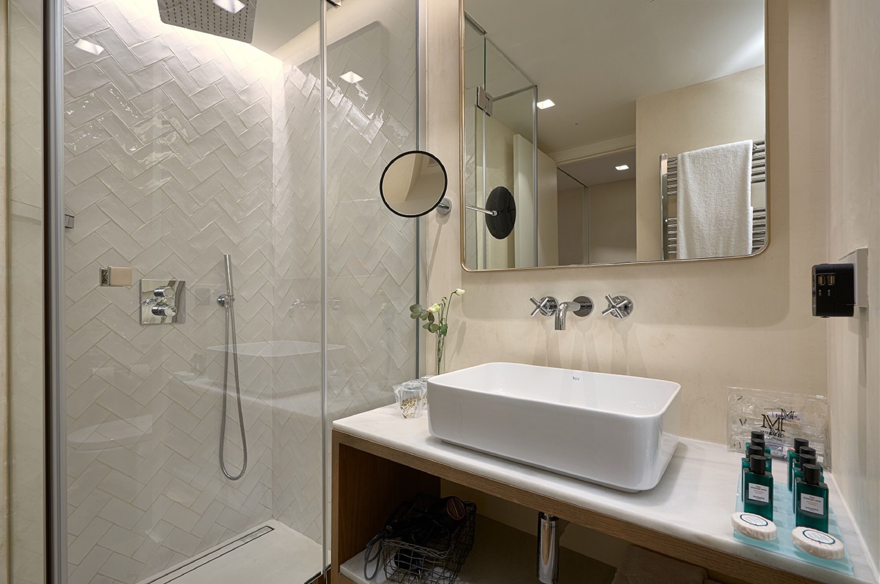 A modern bathroom with a glass-enclosed shower, a white sink, and a large mirror.