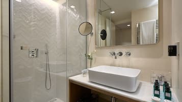 A modern bathroom with a glass-enclosed shower, a white sink, and a large mirror.