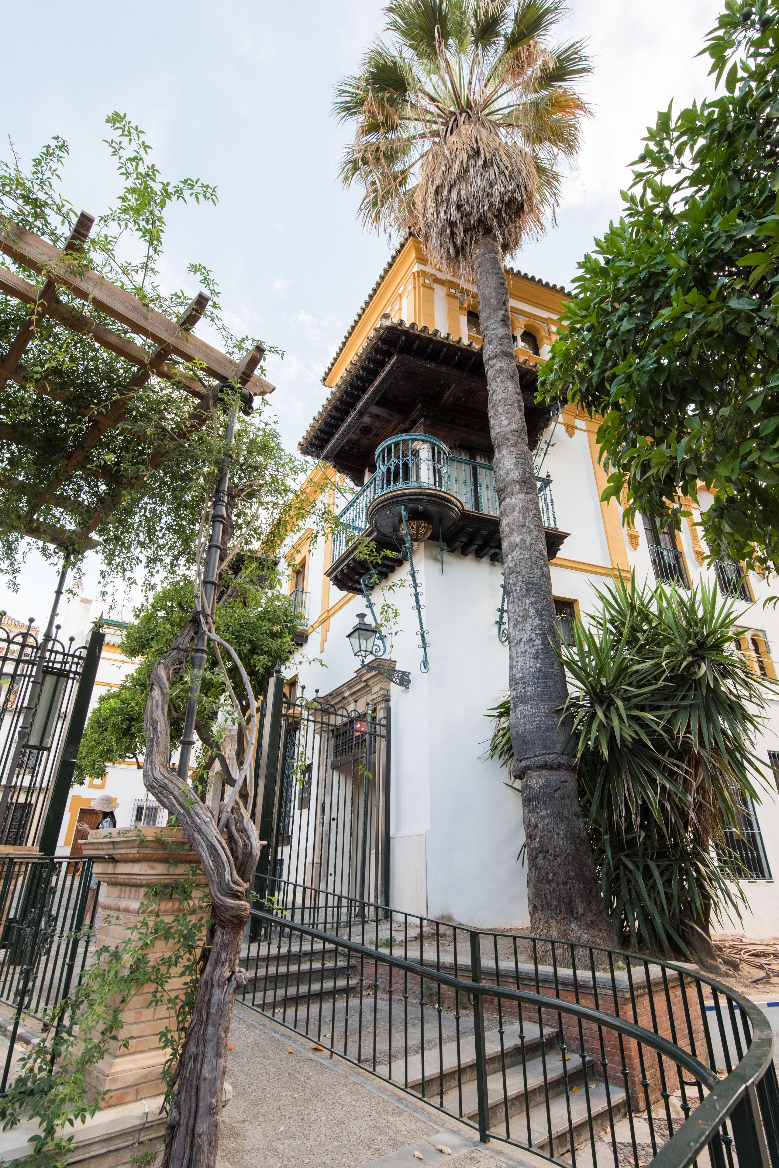 A building with a white facade, a balcony, and a palm tree.