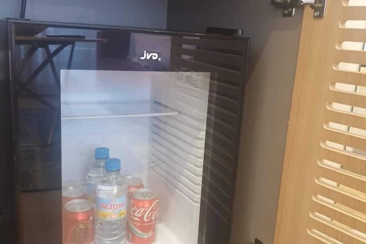 Ein Kühlschrank mit Glastür, der eine Wasserflasche, eine Cola-Dose und eine Flasche Getränke enthält.