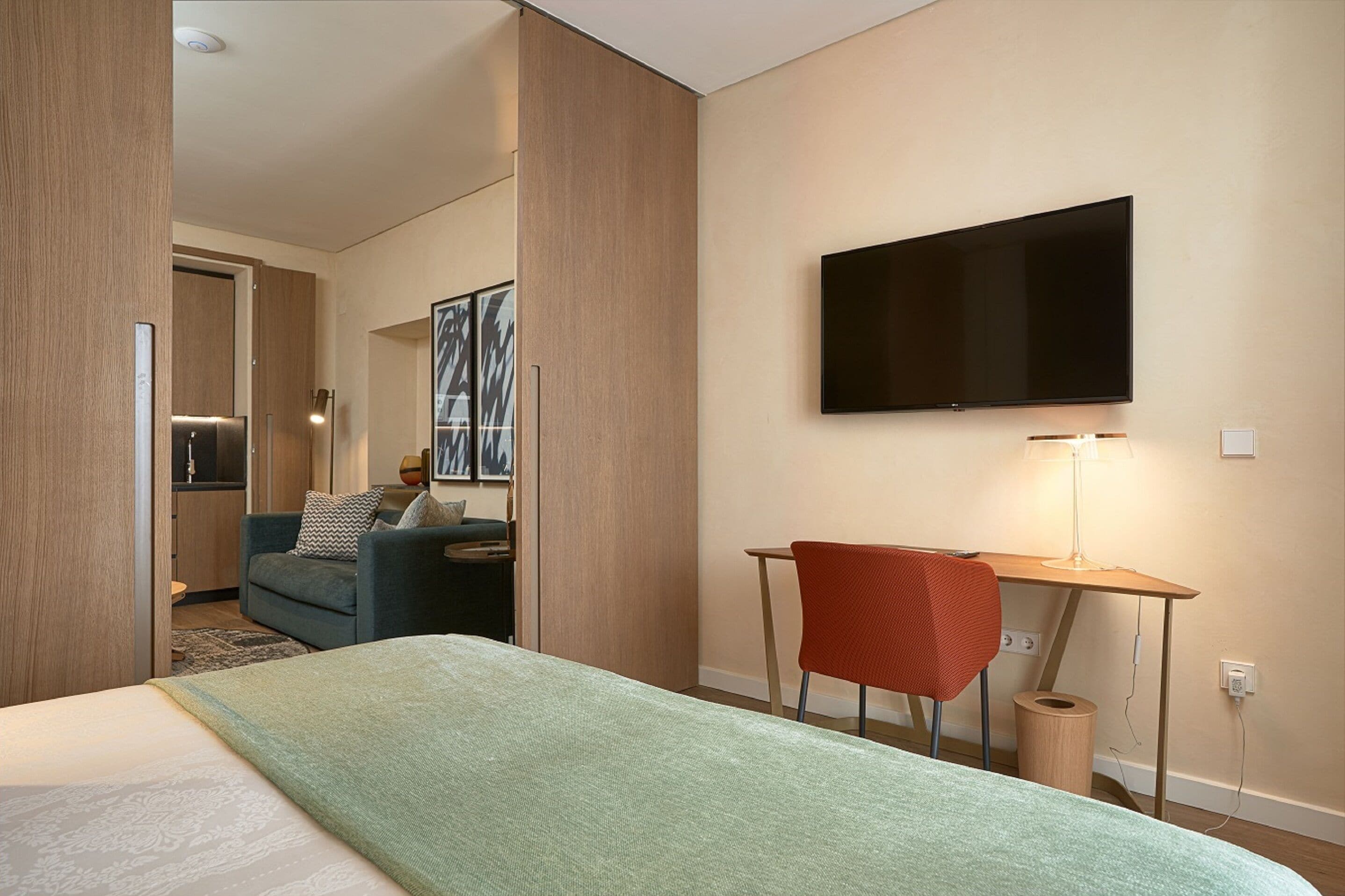 Une chambre d’hôtel avec un lit, un bureau, une chaise, une télévision et un canapé.