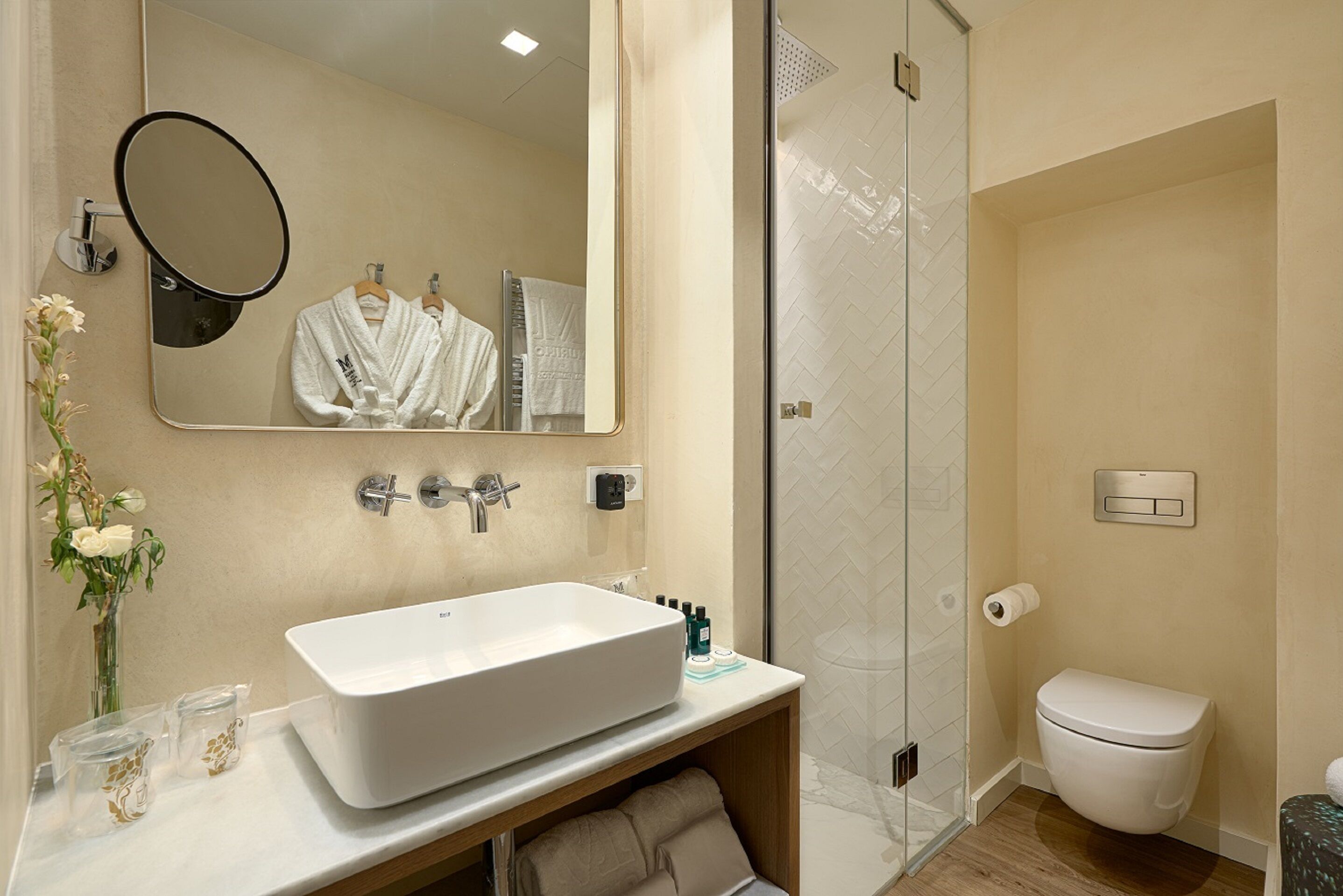 A bathroom with a large mirror, a sink, a shower, and a toilet.