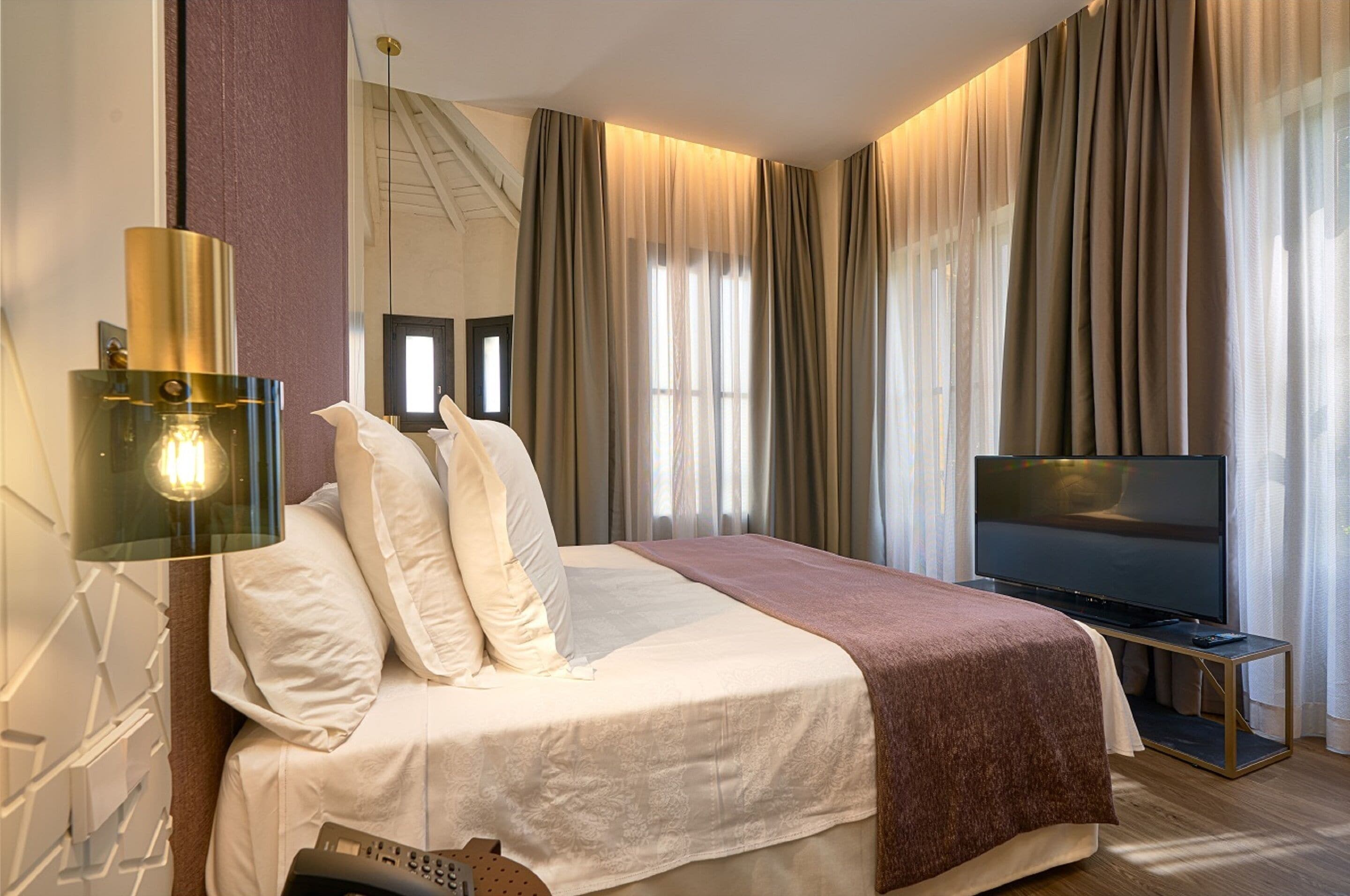 Una habitación de hotel con una cama, un televisor y una lámpara de pared.