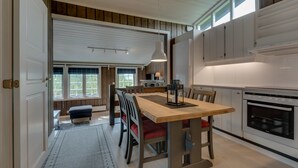 A modern kitchen with a large dining table, wooden cabinets, and a built-in oven. - Bitigrenda H (Øystre Slidre)