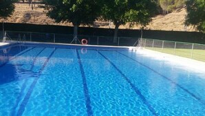 A clear swimming pool with lane dividers, surrounded by a fence and trees.