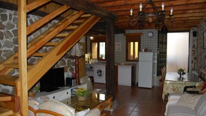 A rustic interior with a wooden staircase, a dining area, and a kitchen.