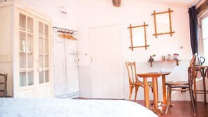 Una habitació amb un llit, una taula de fusta amb caires, un armari blanc i una porta amb disseny rústic.