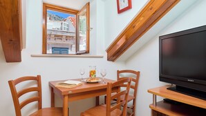 A room with a wooden table, two chairs, a television, and a window with a view of buildings. - Hedera Estate, Hedera A21 Apartment (Dubrovnik)
