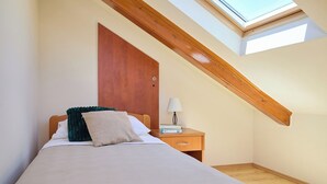 A bedroom with a skylight, a bed with pillows, a bedside table with a lamp, and a wooden ceiling beam. - Hedera Estate, Hedera A21 Apartment (Dubrovnik)