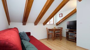A cozy room with a red sofa, a small wooden table, and a TV. - Hedera Estate, Hedera A21 Apartment (Dubrovnik)