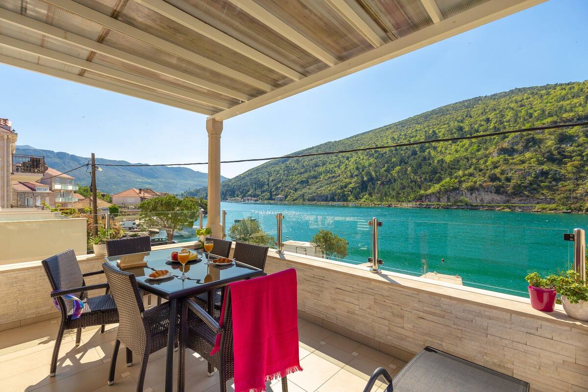 Una terraza con mesa y sillas, con vistas a un lago y montañas.
