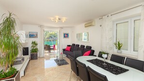 A modern living room with a dining area, a sofa with red cushions, and potted plants. - Hedera Estate, Hedera A24 (Dubrovnik)
