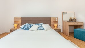 Um quarto bem organizado com cama, mesas de cabeceira, escrivaninha e uma cadeira.