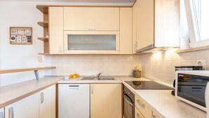 Uma cozinha moderna com armários claros, uma máquina de lavar louça, forno e micro-ondas.