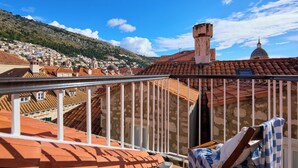 A balcony with a view of a town, a tiled roof, and a building with a dome. - Hedera Estate, Hedera A31 Apartment (Dubrovnik)