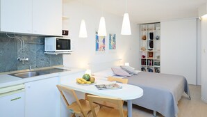A compact kitchen with a microwave, sink, and a dining area with a table and chairs. - Hedera Estate, Hedera Studio 6 (Dubrovnik)