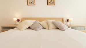 A neatly made bed with a headboard, two bedside tables with lamps, and two framed pictures on the wall. - Hedera Estate, Hedera A13 (Dubrovnik)