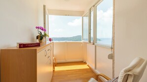 A room with a wooden desk, a chair, a window with a view of the sea, and a small plant on the desk. - Hedera Estate, Hedera A13 (Dubrovnik)