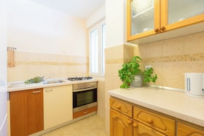 A kitchen with wooden cabinets, a stove, an oven, a sink, and a potted plant. - Hedera Estate, Hedera A13 (Dubrovnik)