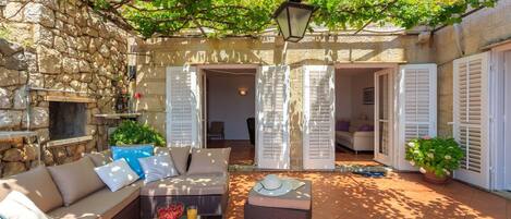 A cozy outdoor seating area with a stone wall, wicker furniture, and a potted plant.