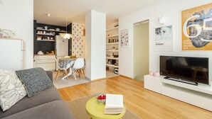 A modern living room with a sofa, a coffee table, a TV, and a dining area with a table and chairs. - Hedera Estate, Hedera A29 (Dubrovnik)