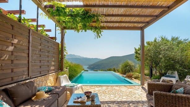A poolside area with a view of mountains, a pergola with greenery, and outdoor seating. - Hedera Estate, House Hedera (Dubrovnik)