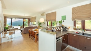 A spacious kitchen with a dining area, large windows, and a view of the outdoors. - Hedera Estate, House Hedera (Dubrovnik)